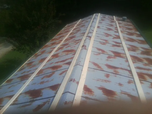Rusted metal roof panels with new wood purlins before replacement — Storm Damage Roof Repair in Spring Creek by Roofing Brothers