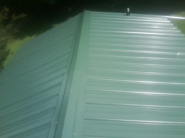 New green metal panels meeting at the ridge of a roof — Flat Roof Repair work by our crew in Spring Creek
