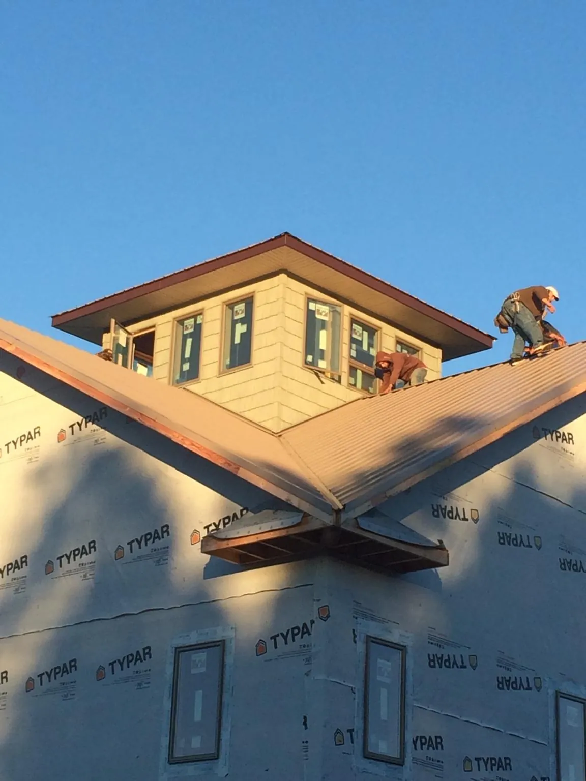 Roofers working around a rooftop cupola on a new metal roof at sunset — Roof Waterproofing in Spring Creek by Roofing Brothers